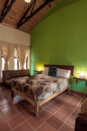ein Schlafzimmer mit einem Bett und einer grünen Wand in der Unterkunft Cabaña Libélula para parejas in Mascota
