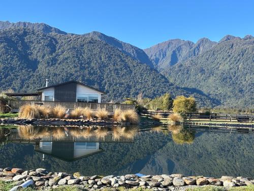 a house on a lake with mountains in the background at Glacier Lake House in Tatare