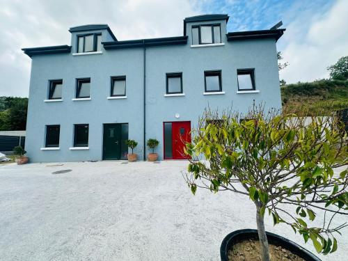 a blue building with a red door and a plant at Railway House, Halfway in Ballinhassig