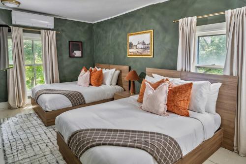 two beds in a room with green walls and windows at Hudson Valley Hot Tub Sauna Fire Pit Games in Hudson