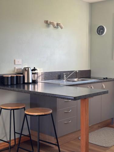 a kitchen with a sink and two bar stools at Glacier Cottage in Tatare