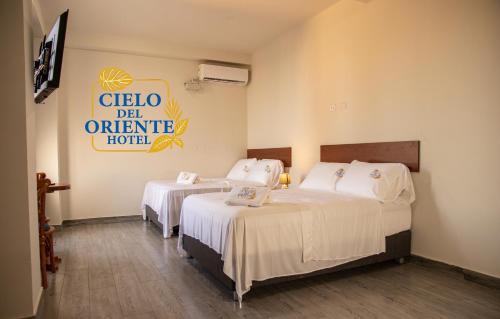 two beds in a room with a sign on the wall at Cielo del Oriente Hotel in Pucallpa
