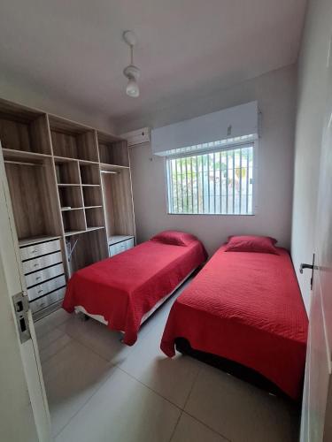 2 camas en un dormitorio con sábanas rojas y ventana en Casa com piscina no Aracagy 2 km da praia, en São Luís