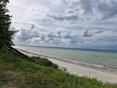 a beach with a cloudy sky and the ocean at 6 person holiday home in Nordborg-By Traum in Nordborg