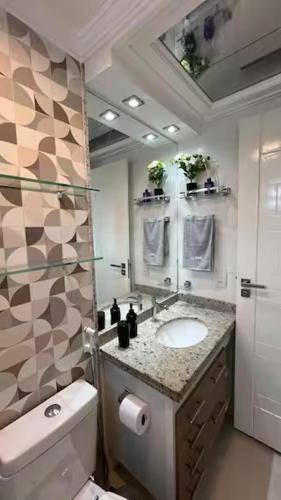 a bathroom with a sink and a toilet and a mirror at Studio Luxuoso in Cabo Frio