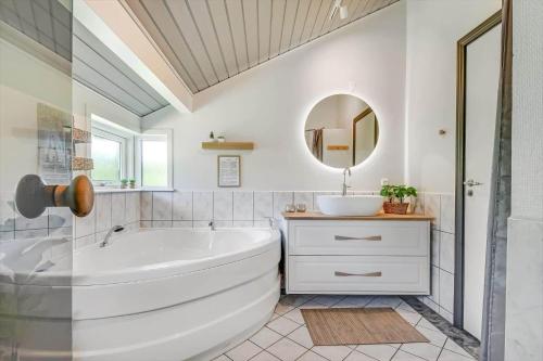 a bathroom with a tub and a sink and a mirror at C11330-Tarm-Blabaervej-14 in Tarm