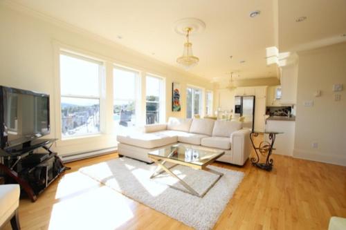 Una sala de estar con un sofá blanco y un televisor. en HarbourGate Condos & Studios, en St. John's