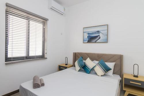 a white bedroom with a bed and two windows at Rocky 35 in Grand-Baie