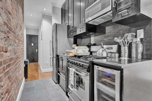 a kitchen with stainless steel appliances and a brick wall at Modern 3BR in Gramercy -Near Union Sq NYU in New York