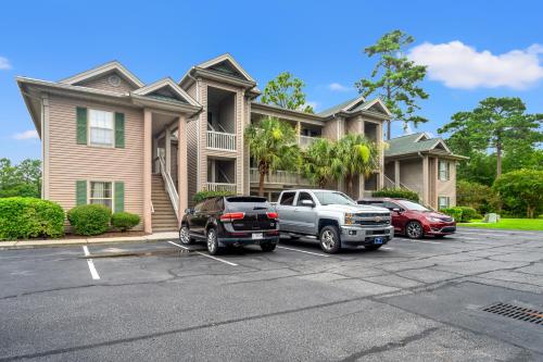 two cars parked in a parking lot in front of a house at Charming upgraded 2-bed condo in amazing Pawleys Island True Blue Golf Course in Pawleys Island