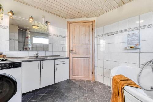 a bathroom with a tub and a sink and a washing machine at C11324-Tarm-Blabaervej-6 in Tarm