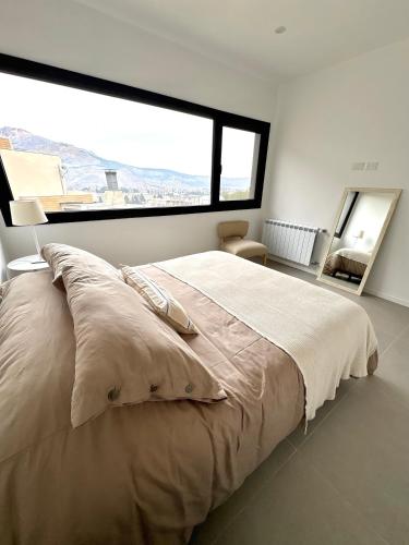 a bedroom with a large bed with a large window at Cantera Tempo 2 in Esquel