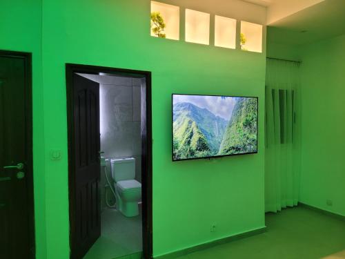 Un baño verde con un inodoro y un cuadro en la pared. en Sheyllo Suites Abidjan - Cocody, en Abiyán