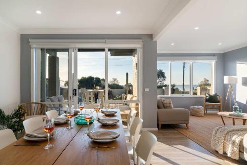Un comedor con una mesa y una sala de estar. en Shoreline Sanctuary - Panoramic Views Spa Tennis, en Safety Beach