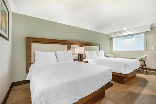 a hotel room with two beds and a window at Best Western PLUS Burnaby Hotel in Burnaby