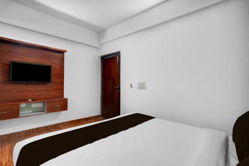 a bedroom with a bed and a flat screen tv at Super Townhouse Whitefield Railway Station Formerly Kadugudi Whitefield in Bengaluru