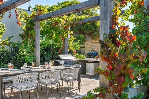 a patio with a table and chairs and a grill at Beachfront Luxury - Panoramic Views Games Wineries in Safety Beach