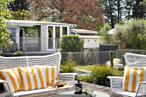 a patio with two white wicker chairs and a house at Hillside Cottage - Wineries Pool in Red Hill South