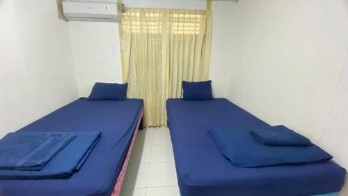 two beds in a small room with a window at 88HappyHomestay in Luwuk