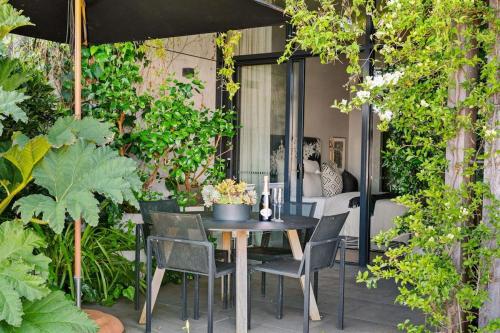 een tafel en stoelen op een patio met planten bij Martha's Retreat - Waterfront Luxury in Safety Beach