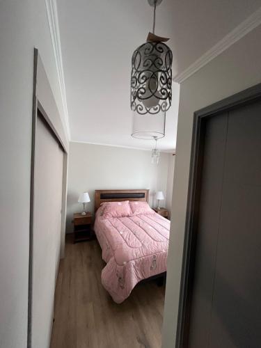 a bedroom with a pink bed and a chandelier at Cómoda casa nueva 3 D 2 B in La Serena