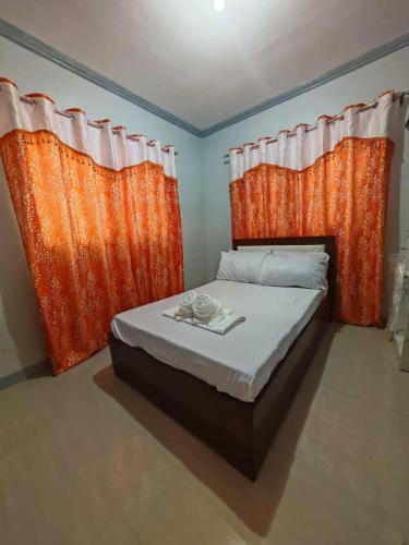 a bedroom with an orange curtain and a bed witharios at Grace Abode Haven in General Santos