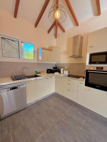 a kitchen with white cabinets and a ceiling at Villa SAADA cosy avec piscine, jacuzzi et sauna in Le Vauclin