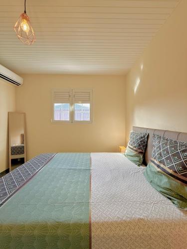 a bedroom with a large bed and two windows at Villa SAADA cosy avec piscine, jacuzzi et sauna in Le Vauclin