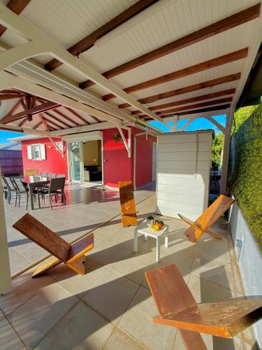 a patio with chairs and a table and awning at Villa SAADA cosy avec piscine, jacuzzi et sauna in Le Vauclin