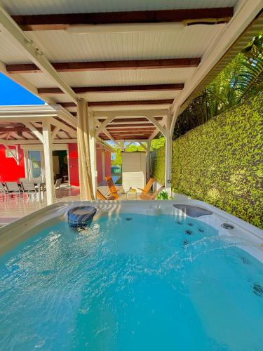a large swimming pool under a covered patio at Villa SAADA cosy avec piscine, jacuzzi et sauna in Le Vauclin