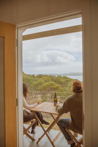 two people sitting at a table with a view of the ocean at Sea Loft Kangaroo Island in Kingscote
