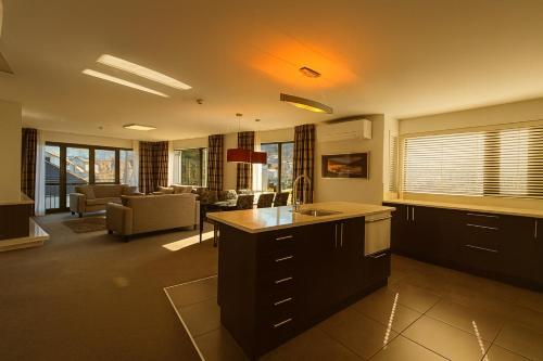 a kitchen with a sink and a living room at Village Lake Luxury Apartments in Hanmer Springs