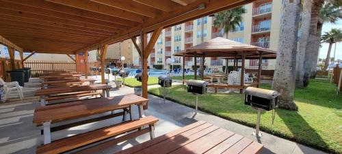 a row of benches and an umbrella on a patio at Private Beach Access Pool & Hot Tub BBQ Pits Gulfview II #408 home in South Padre Island