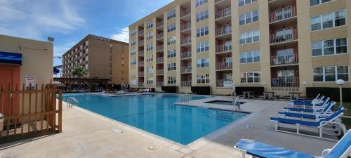 a swimming pool with chairs and a building at Private Beach Access Pool & Hot Tub BBQ Pits Gulfview II #408 home in South Padre Island