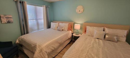 a bedroom with two beds and a clock on the wall at Private Beach Access Pool & Hot Tub BBQ Pits Gulfview II #408 home in South Padre Island