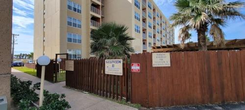 a fence in front of a building with signs on it at Private Beach Access Pool & Hot Tub BBQ Pits Gulfview II #408 home in South Padre Island