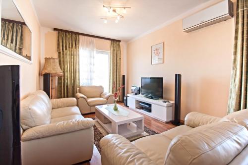 a living room with white furniture and a flat screen tv at Apartments Villa Excellente Belvedere in Pula