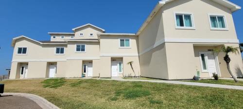 a large white house with a grass yard at Bungalow Tarvana #2 home in Port Isabel