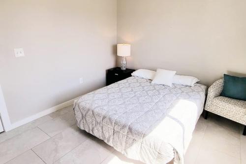 a white bedroom with a bed and a chair at Bungalow Tarvana #2 home in Port Isabel