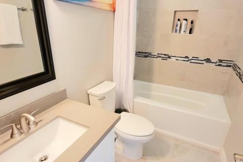 a white bathroom with a toilet and a tub and a sink at Bungalow Tarvana #2 home in Port Isabel