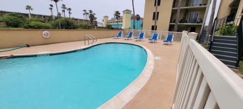 Una piscina con sillas azules al lado de un edificio. en Habitat #23 home, en South Padre Island