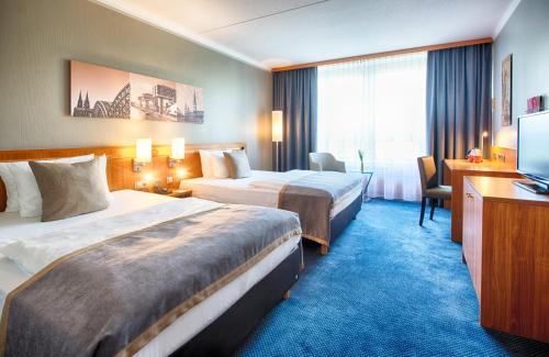 a hotel room with two beds and a television at Leonardo Hotel Köln Bonn Airport in Cologne