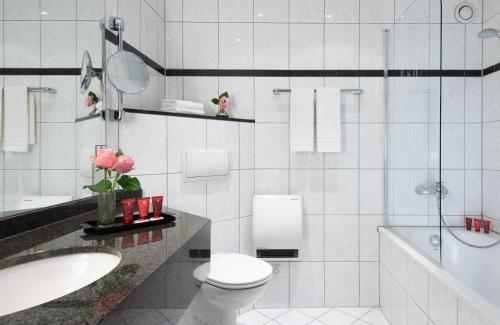 a bathroom with a toilet and a sink and a tub at Leonardo Hotel Köln Bonn Airport in Cologne
