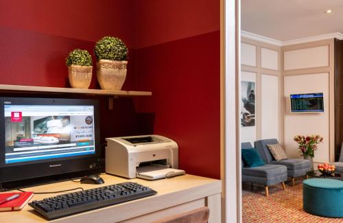 a desk with a computer monitor and a printer at Leonardo Hotel Köln Bonn Airport in Cologne
