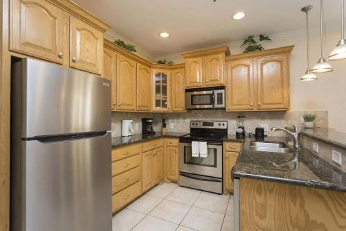 Una cocina con gabinetes de madera y un refrigerador de acero inoxidable. en Dom's Beach Retreat home, en South Padre Island