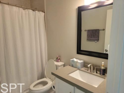 a bathroom with a toilet and a sink and a mirror at New Waterfront Bungalow - Fishermans Paradise - Bungalow Tarvana in South Padre Island