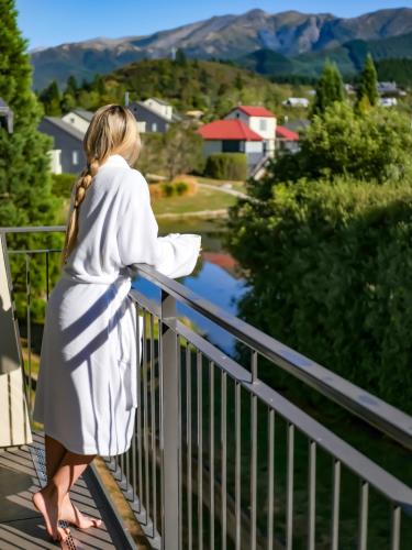a woman standing on a balcony looking at the mountains at Village Lake Luxury Apartments in Hanmer Springs