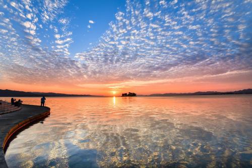 a person standing on a dock watching the sunset at Matsue Plaza Hotel in Matsue