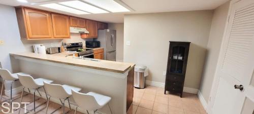 a kitchen with a bar with white chairs in it at Saida Towers IV #108 condo in South Padre Island