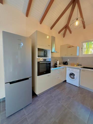 a kitchen with a white refrigerator and a dishwasher at Villa LUGNA piscine privée in Le Vauclin